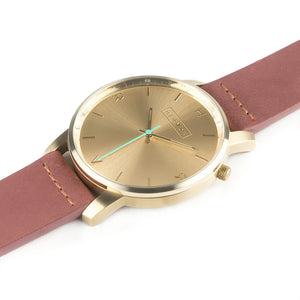 All gold Hervor watch with dusty rose dark pink leather strap and a turquoise accent second hand