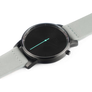 All black Hervor watch with dove grey leather strap and a turquoise accent second hand