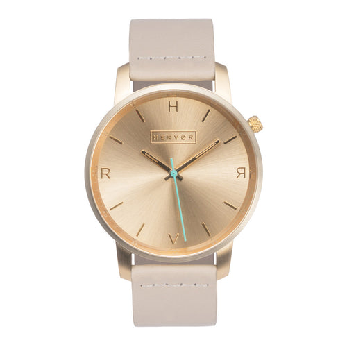 All gold Hervor watch with light pink skin tone leather strap and a turquoise accent second hand
