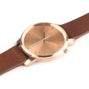 All rose gold Hervor watch with fox brown leather strap and a turquoise accent second hand